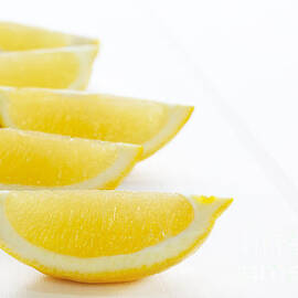Lemon Wedges on White Background by Colin and Linda McKie