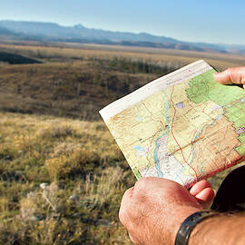 Man Reading A Map While Backpacking by Justin Bailie