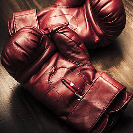 Retro red boxing gloves on wooden training bench by Jorgo Photography