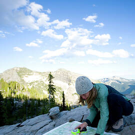 Woman Using A Map And Compass While by Woods Wheatcroft