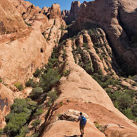 A Man Hiking Next To A Sandstone Arch by Whit Richardson