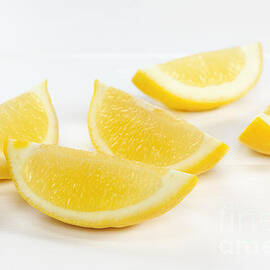 Lemon Wedges on White Background by Colin and Linda McKie