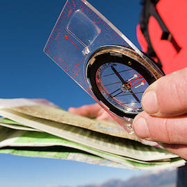 Man Reading A Map While Backpacking by Justin Bailie