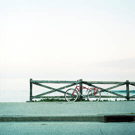 A Bicycle Leans Against A Wood Railing by Andrew Querner