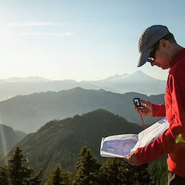 A Man Uses A Compass And Paper Map by Christopher Kimmel