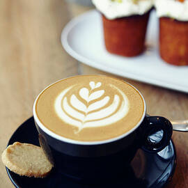 Cup Of Coffee With Leaf Pattern On by Jake Curtis