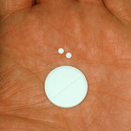 Hand Holding Pills Of Differing Sizes by Science Photo Library