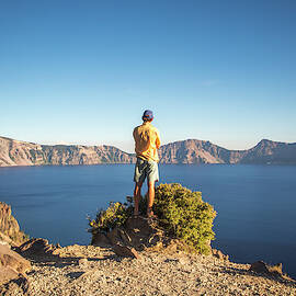 Man Standing On Shore Of Crater Lake by David Hanson