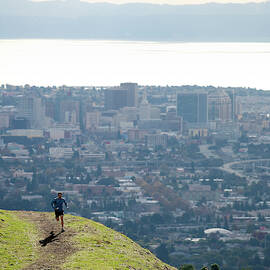 Man Trail Running Above A City by Corey Rich