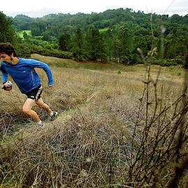 Man Trail Running On A Foggy Day by Corey Rich