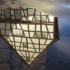 Reflection of a beautiful old half-timbered house in a puddle of water by Matthias Hauser