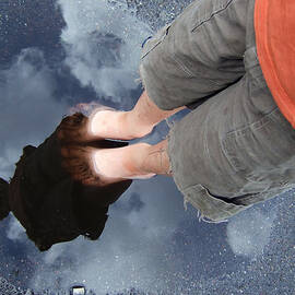 Reflection of boy in a puddle of water by Matthias Hauser