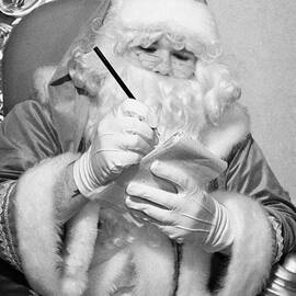 Santa sitting on his throne writing a list using pencil and notepad in grotto set up by Joe Fox