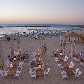 Tables And Chairs On Beach At Dusk by Barry Winiker