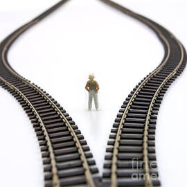 Figurine between two tracks leading into different directions  symbolic image for making decisions. by BERNARD JAUBERT