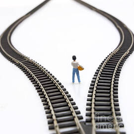 Figurine between two tracks leading into different directions symbolic image for making decisions. by BERNARD JAUBERT