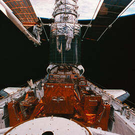 Astronauts Working On A Satellite Docked On The Space Shuttle by Stockbyte