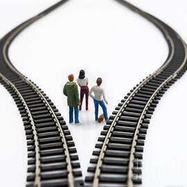 Figurines between two tracks leading into different directions symbolic image for making decisions. by BERNARD JAUBERT