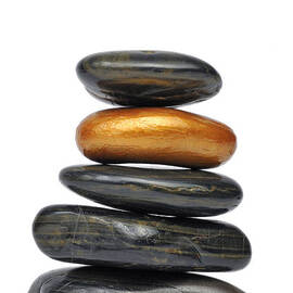 Golden pebble in stack of black pebbles by Sami Sarkis Photography