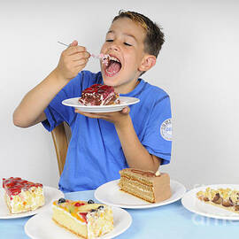 Hungry boy eating lot of cake