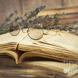 Old books open on wooden table  by Sandra Cunningham