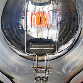 Red filament inside illuminated light bulb by Sami Sarkis Photography