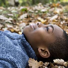 Smiling Boy Lying On Autumn Leaves