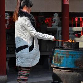Chinese woman burns incense offering at Taoist temple by Imran Ahmed