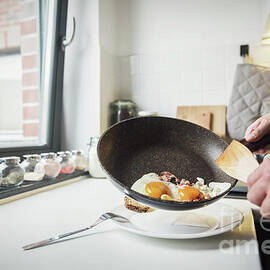 Man putting fried eggs on the plate by Michal Bednarek