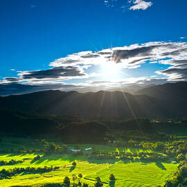 Sunrays flood farmland during sunset