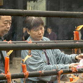 Visitors Light Candles At A Buddhist by Inga Spence