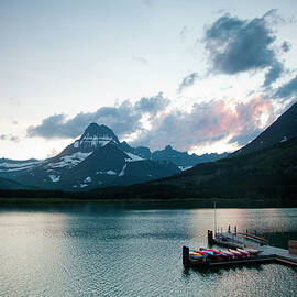 A Lake With A Dock And Kayaks At Dusk by Michael Hanson