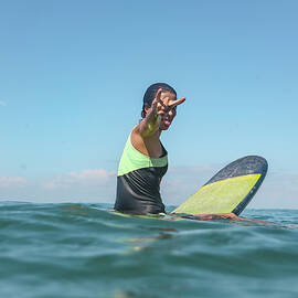 Female Surfer Sitting On Surfboard by Cavan Images