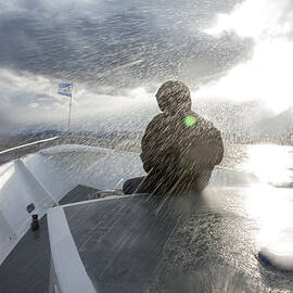 Person In Waterproofs Sitting In Front Of Boat Sailing In Rain Storm, Ushuaia, Tierra Del Fuego, Argentina by Diana Deak