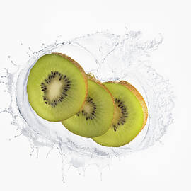 Three Slices Of Kiwi Splashing In Liquid by Cadalpe