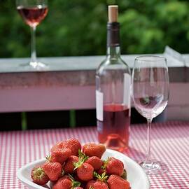 A Bowl Of Strawberries And Some Ros Wine On A Table On The Balcony, The Table Covered With A Gingham Tablecloth by Heinze, Winfried