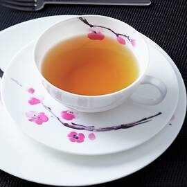 A Place Setting For Afternoon Tea, With A Flower Design, On A Black Surface by Taube, Franziska