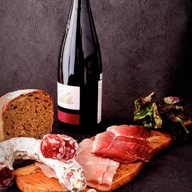 A Selection Of Cold Meats With Bread, A Bottle Of Red Wine And A Corkscrew by Jamie Watson