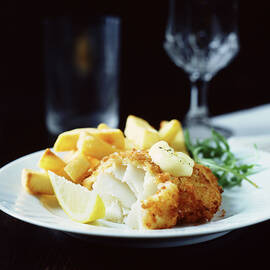 Breaded Fish With Chips, Rocket And Lemon Slice On White Plate by Diana Miller