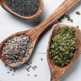 Chia Seeds, Sunflower Seeds And Pumpkin Seeds On Wooden Spoons by Spyros Bourboulis