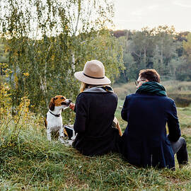 Couple Is Walking In The Park Playing With A Beagle Dog Having Fun by Cavan Images / Orest Filin