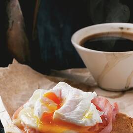 Ham And Cheese On Toast Topped With A Poached Egg On A Piece Of Baking Paper Served With A Cup Of Coffee by Natasha Breen