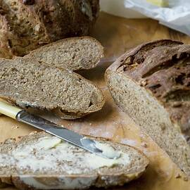 Loaves And Slices Of Walnut Bread With Butter On A Cutting Board by Joy Skipper Foodstyling