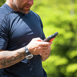 Man Navigates While Hiking Using A Gps Device by Cavan Images