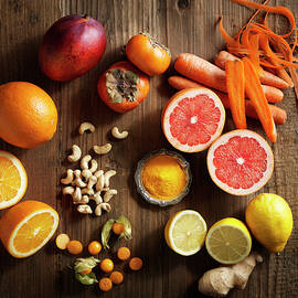 Overhead View Of Orange Fruit And Vegetables On Wood Grain Pattern Background by Wayup Productions