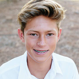 Portrait Of A Handsome Teen Boy With Brown Eyes And Braces by Cavan Images