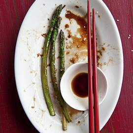 Remains Of A Meal Of Fried Asparagus And Soy Sauce On A Plate With Chopsticks by Studer, Veronika