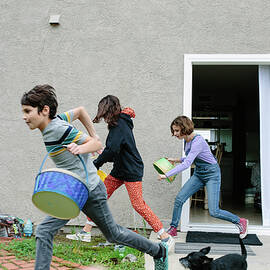 Siblings Dash Outside With Their Empty Easter Baskets To Collect Eggs by Cavan Images
