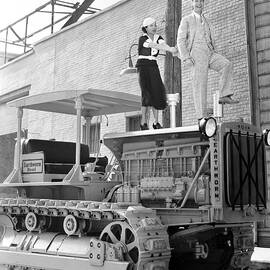 smiling joe e. brown and june travis standing on tractor by Globe Photos