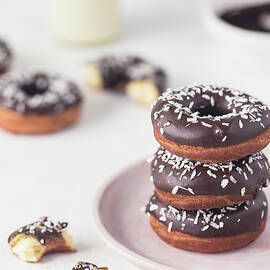 Stack Of A Donuts With Chocolate Glaze And Coconut Shreds by Malgorzata Laniak